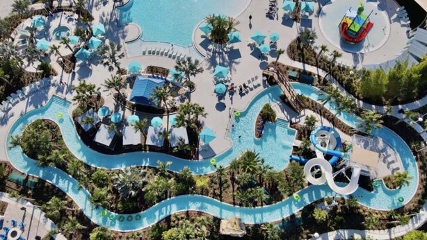 An aerial view of a resort with a winding pool, lounge areas, and palm trees. - Last Minute Disney Getaway! Private Pool & Themed Bedrooms. Book Now! #90485 (Orlando)