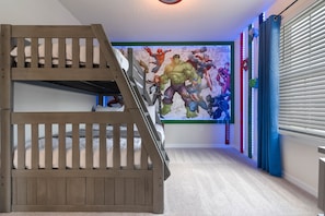Une chambre avec un lit superposé, une fresque représentant des super-héros et une fenêtre avec des stores.