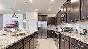 A modern kitchen with dark cabinetry, stainless steel appliances, and a granite countertop. - Last Minute Disney Getaway! Private Pool & Themed Bedrooms. Book Now! #90485 (Orlando)