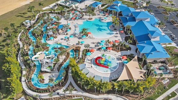 An aerial view of a resort with multiple swimming pools, water slides, and a large central pool.
