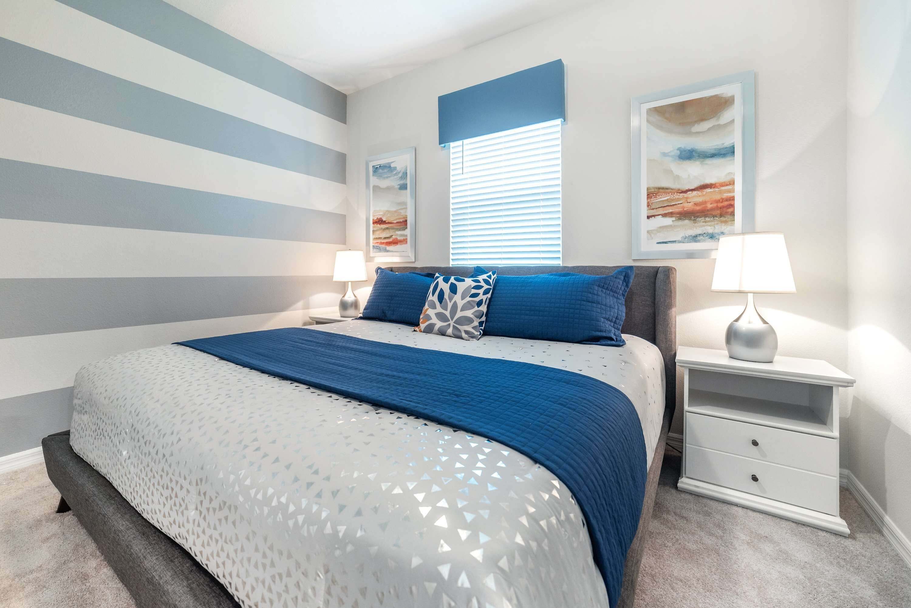 A bedroom with a bed, two bedside tables, and a window with blinds.