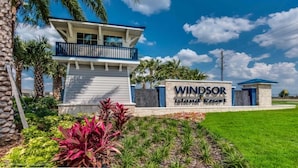 A sign for Windsor Island Resort with a modern building and landscaped garden.