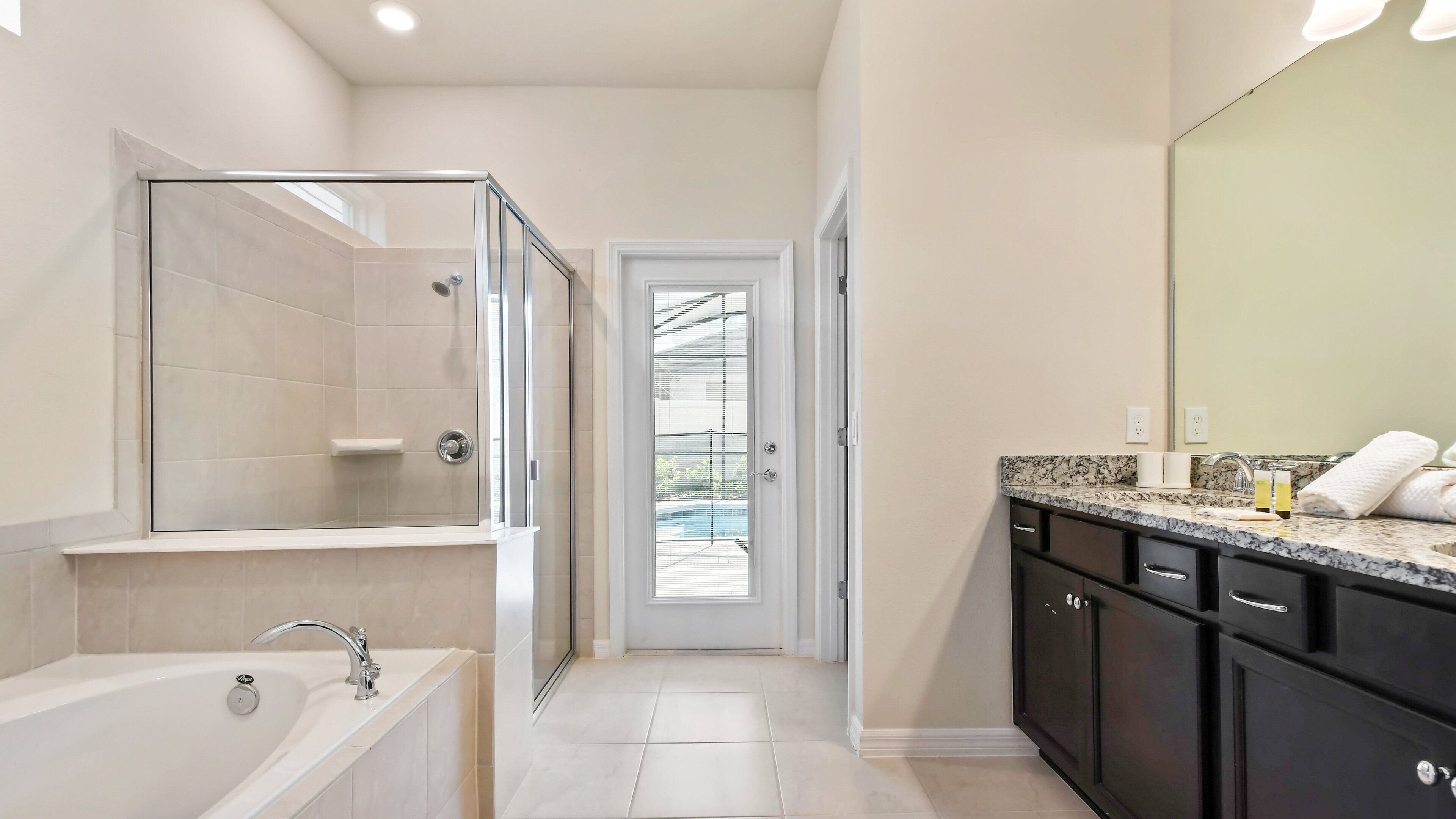 Une salle de bain moderne dotée d’une douche à parois de verre, d’une baignoire, d’un meuble-lavabo et d’un grand miroir.
