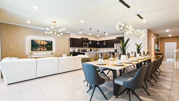 A modern dining area with a long table, multiple chairs, and contemporary lighting fixtures. - Last Minute Disney! Private Pool, Hot Tub, Game Room & Themed Bedrooms. Book Now! #90909 (Orlando)
