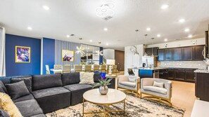 Relax in a cozy seating area with a sofa and coffee table, adjacent to a dining space and kitchen with a large island.