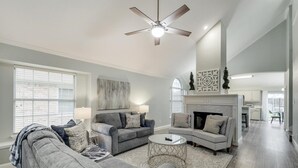 A spacious living room with a fireplace, two sofas, a coffee table, and a ceiling fan. - Lovely Lewisville great location minutes to Denton, Flower Mound, & The Colony! (Lewisville)