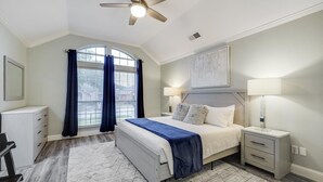 A bedroom with a bed, nightstands, a ceiling fan, a window with curtains, and a painting on the wall. - Lovely Lewisville great location minutes to Denton, Flower Mound, & The Colony! (Lewisville)