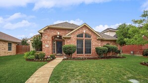 A brick house with a front entrance, a small porch, and a well-maintained lawn. - Lovely Lewisville great location minutes to Denton, Flower Mound, & The Colony! (Lewisville)