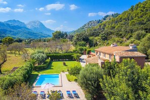 Relax by the serene pool surrounded by lush greenery and a mountainous backdrop.