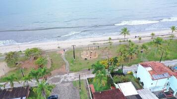Enjoy the serene ocean views and stroll along the sandy beach, surrounded by palm trees and residential buildings.