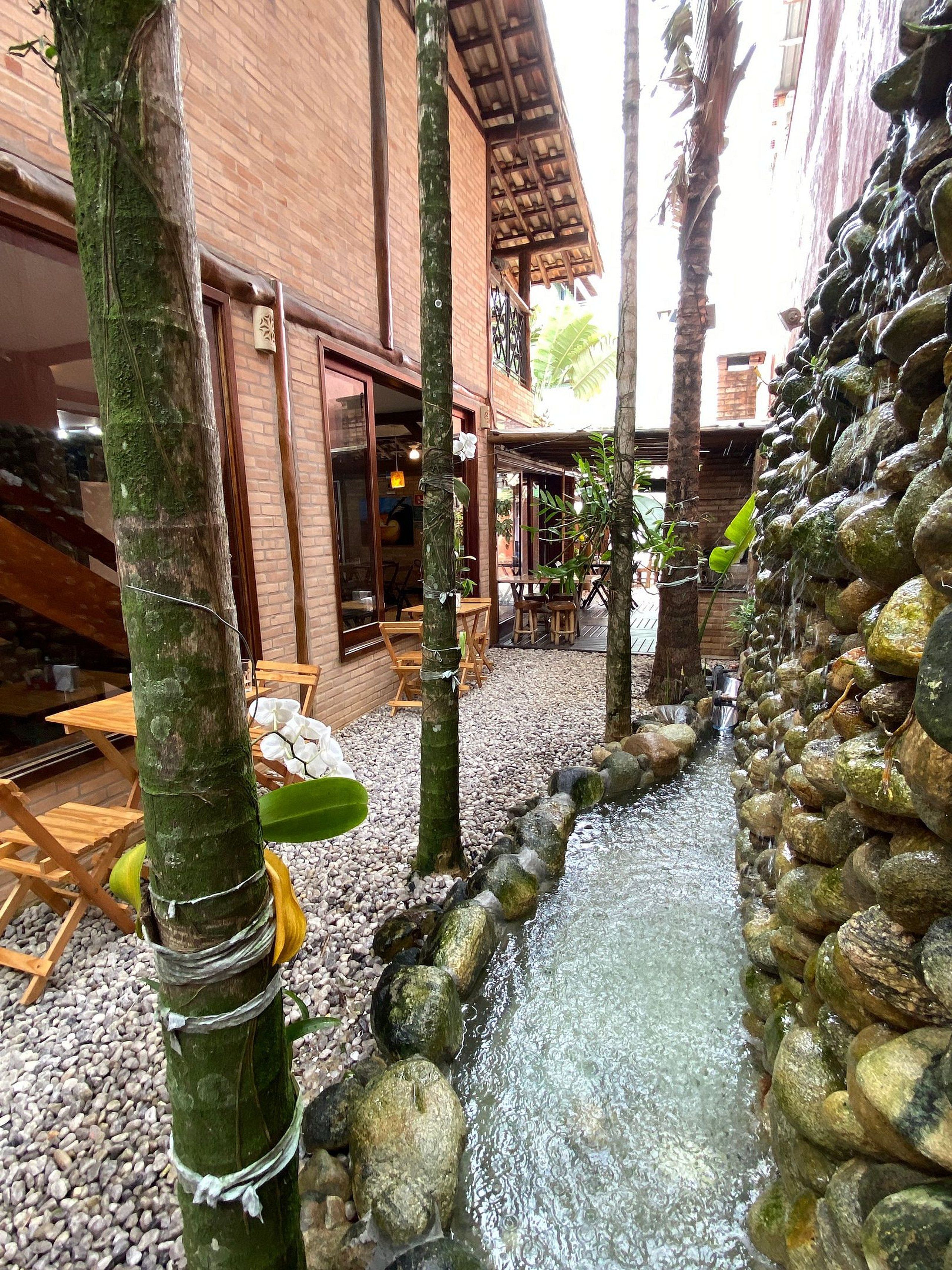 A courtyard with a water feature, wooden furniture, and a brick building.