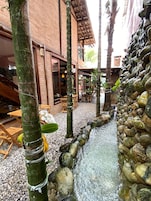 Un patio con fuente de agua, muebles de madera y un edificio de ladrillo.