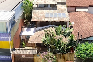 A residential building with a tiled roof, a balcony, and a fenced garden area.
