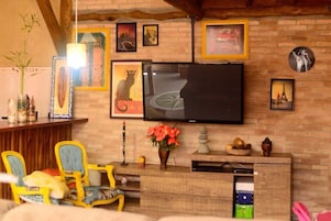 A cozy living room with a brick wall, a flat-screen TV, and a wooden entertainment unit with decorative items.