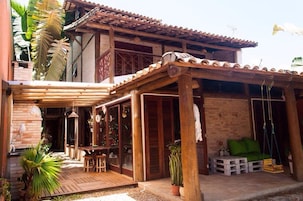 A wooden house with a patio, a swing, and a Christmas tree.