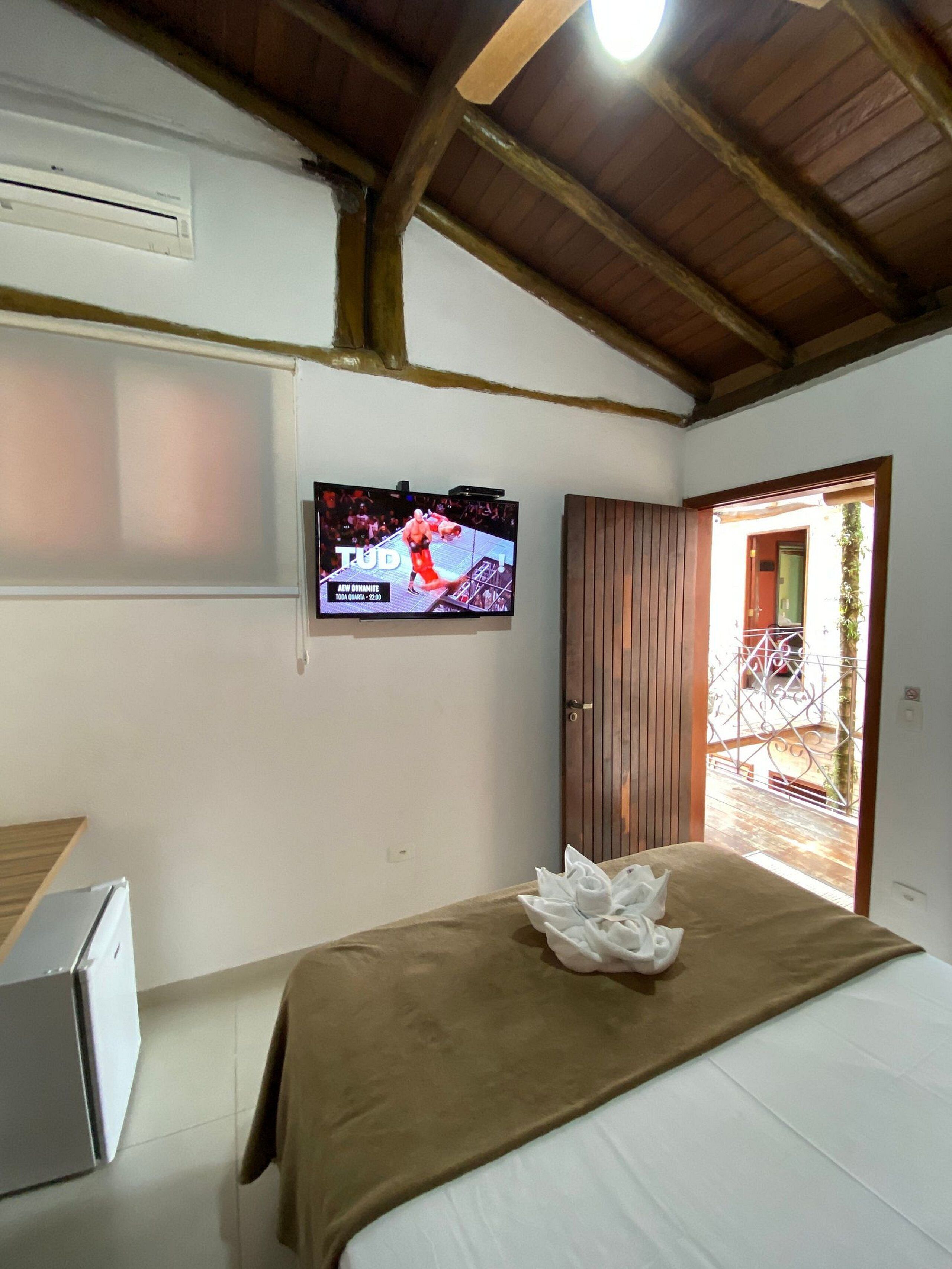 A bedroom with a bed, a television mounted on the wall, and a door leading to an outdoor area.