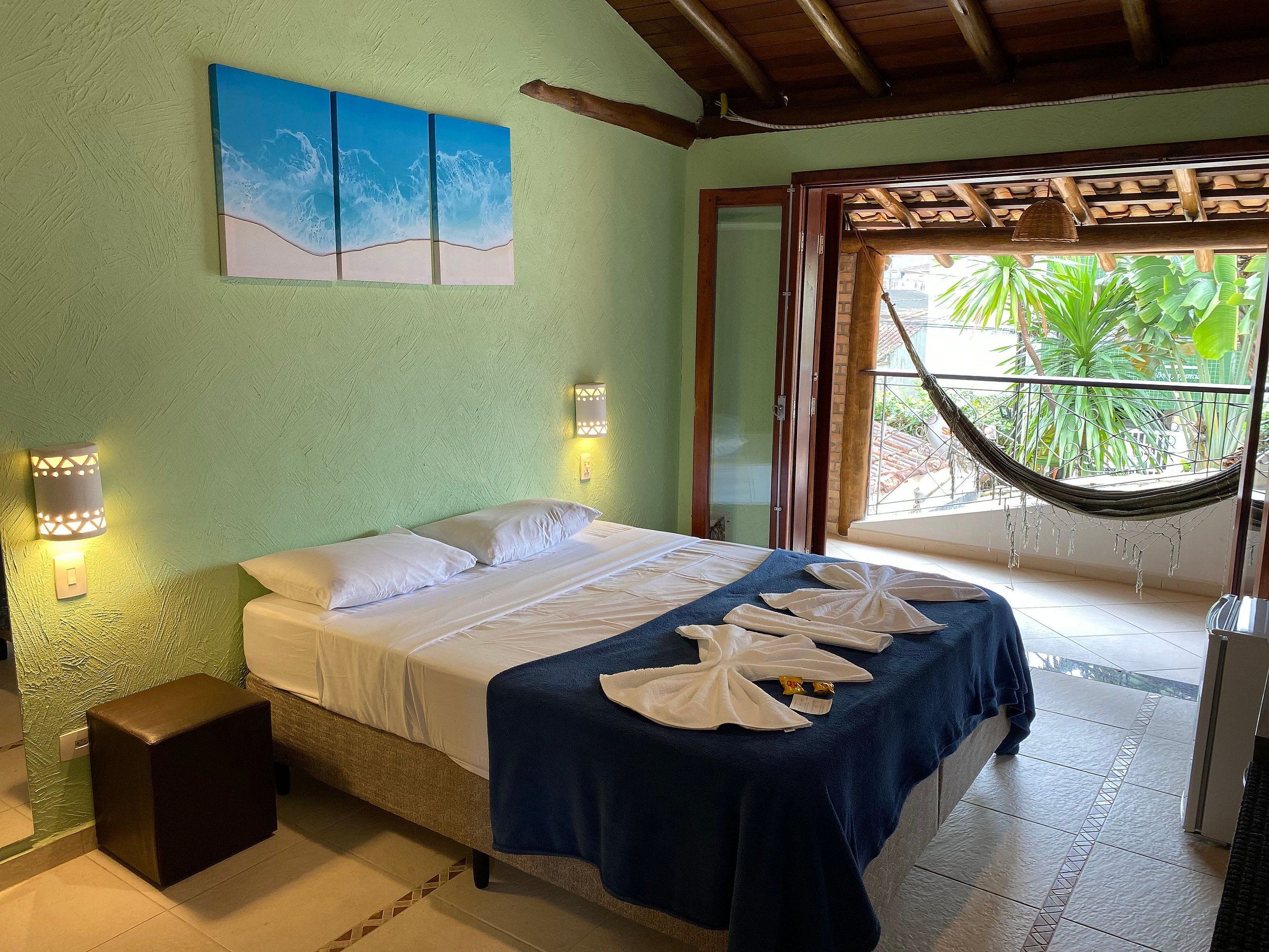Un dormitorio con cama, dos luces empotradas, una hamaca y vistas a la vegetación.
