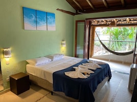 Un dormitorio con cama, dos luces empotradas, una hamaca y vistas a la vegetación.