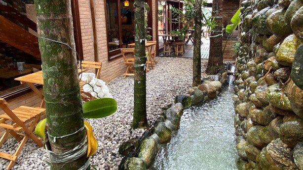 Un patio con fuente de agua, muebles de madera y un edificio de ladrillo.