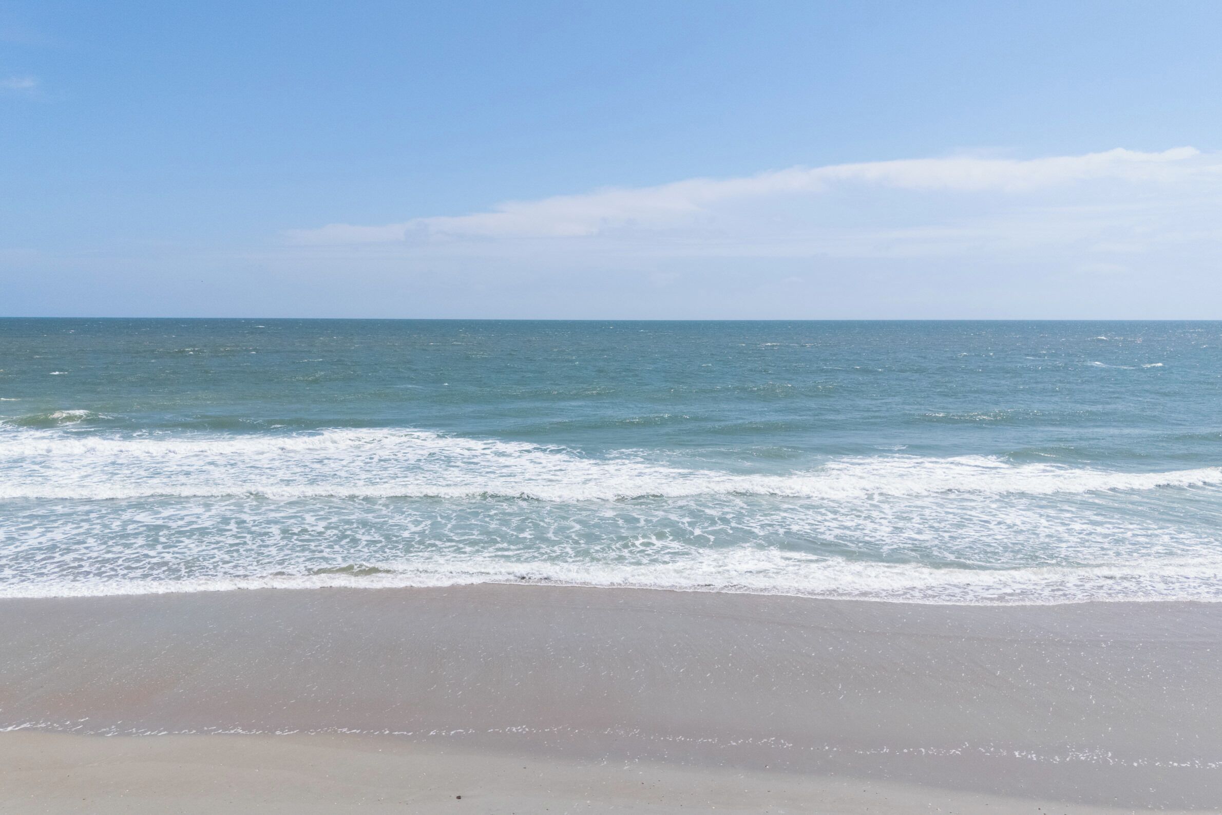 A beach with a clear view of the ocean and a sandy shore.
