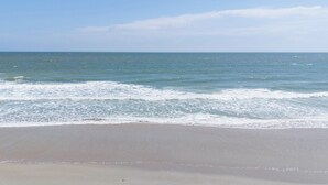 A beach with a clear view of the ocean and a sandy shore.