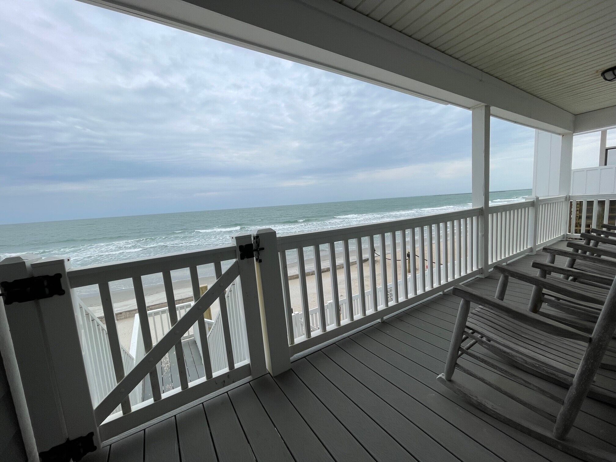 A wooden deck with a railing overlooking the ocean.