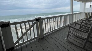 A wooden deck with a railing overlooking the ocean.