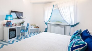 Ein Schlafzimmer mit Bett, Schreibtisch, Stuhl und einem Fenster mit Vorhängen.