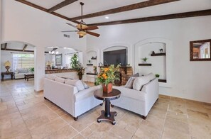 Cozy living area with a high ceiling, fireplace, and large flat-screen TV.