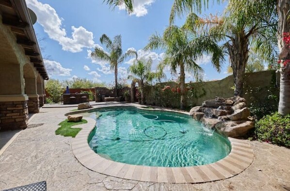 Relax by the pool surrounded by lush vegetation and a soothing waterfall.