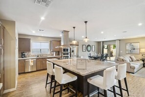 A spacious kitchen with a central island, modern appliances, and a dining area with a sofa and chairs. - Serene Scottsdale Home W/ Pool & Hot Tub (Scottsdale)