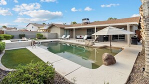 Quintal com piscina, espreguiçadeiras e área de varanda coberta.