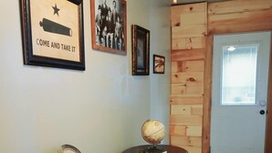 A room with a wooden door, a framed picture with a star and text, a globe on a small table, a chair, and a potted plant. - Cozy Home on Lake Brownwood  (Brownwood)
