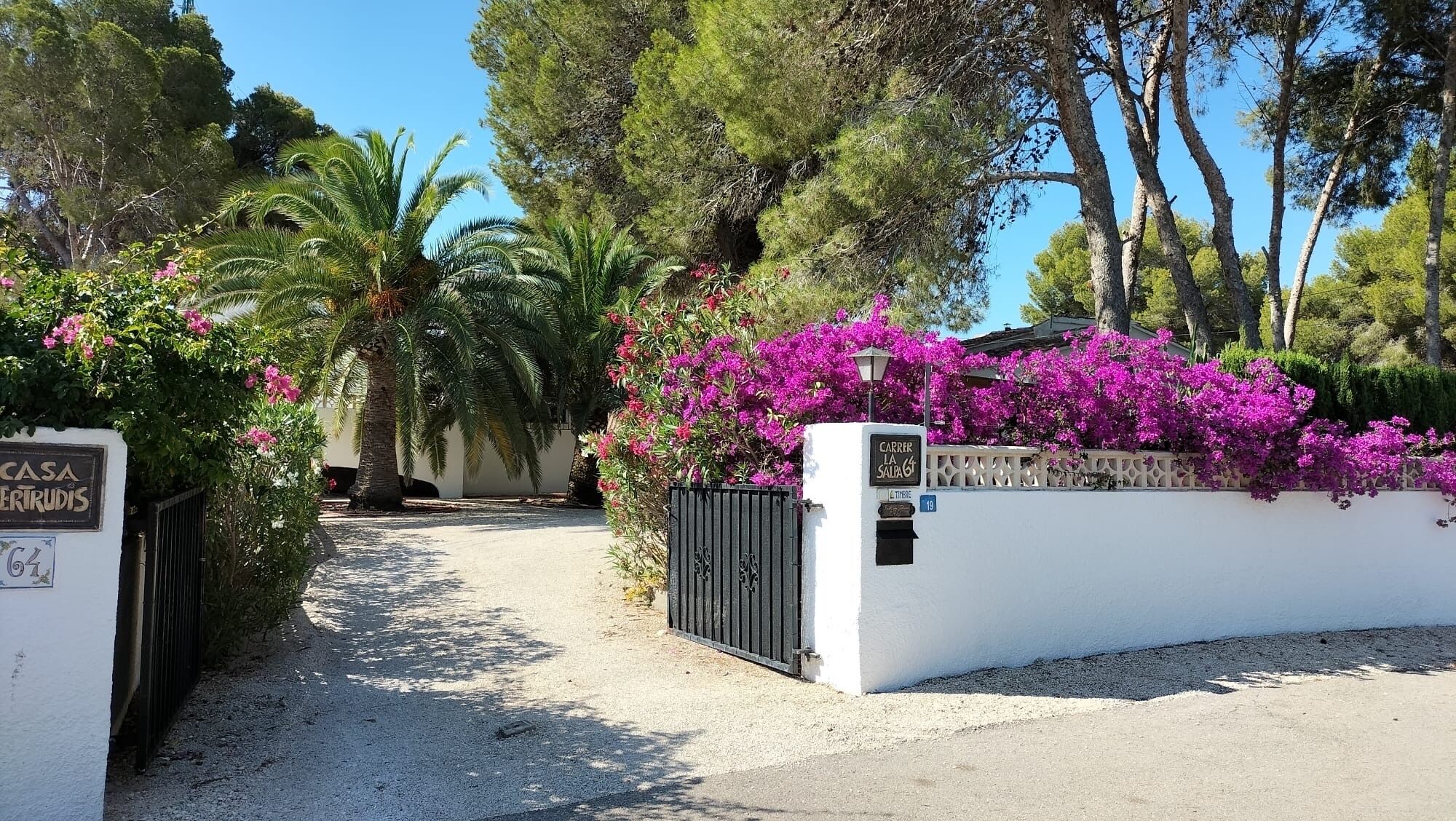 Una entrada con puerta protegida, pared blanca y un letrero que dice "CARRER LA SALPA".
