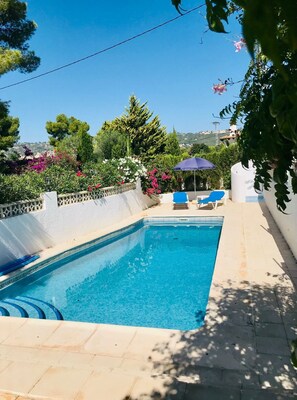 A rectangular swimming pool with a tiled deck, surrounded by lush greenery and a clear blue sky. - Comfortable | Very quiet area | 2km from Cala Cap Blanc - Punta Estrella (VC)