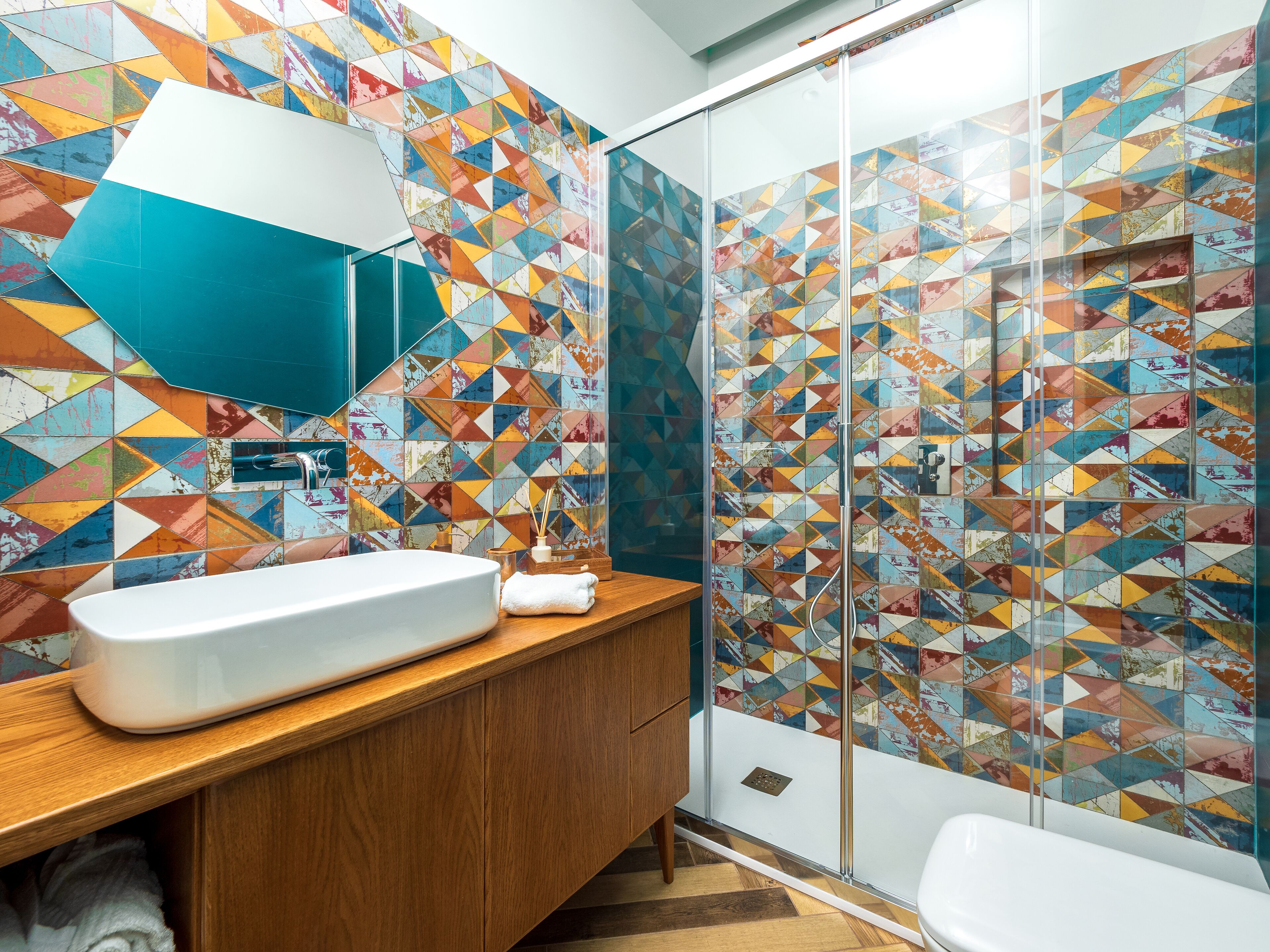 A bathroom with a white sink, wooden vanity, and a glass shower enclosure.