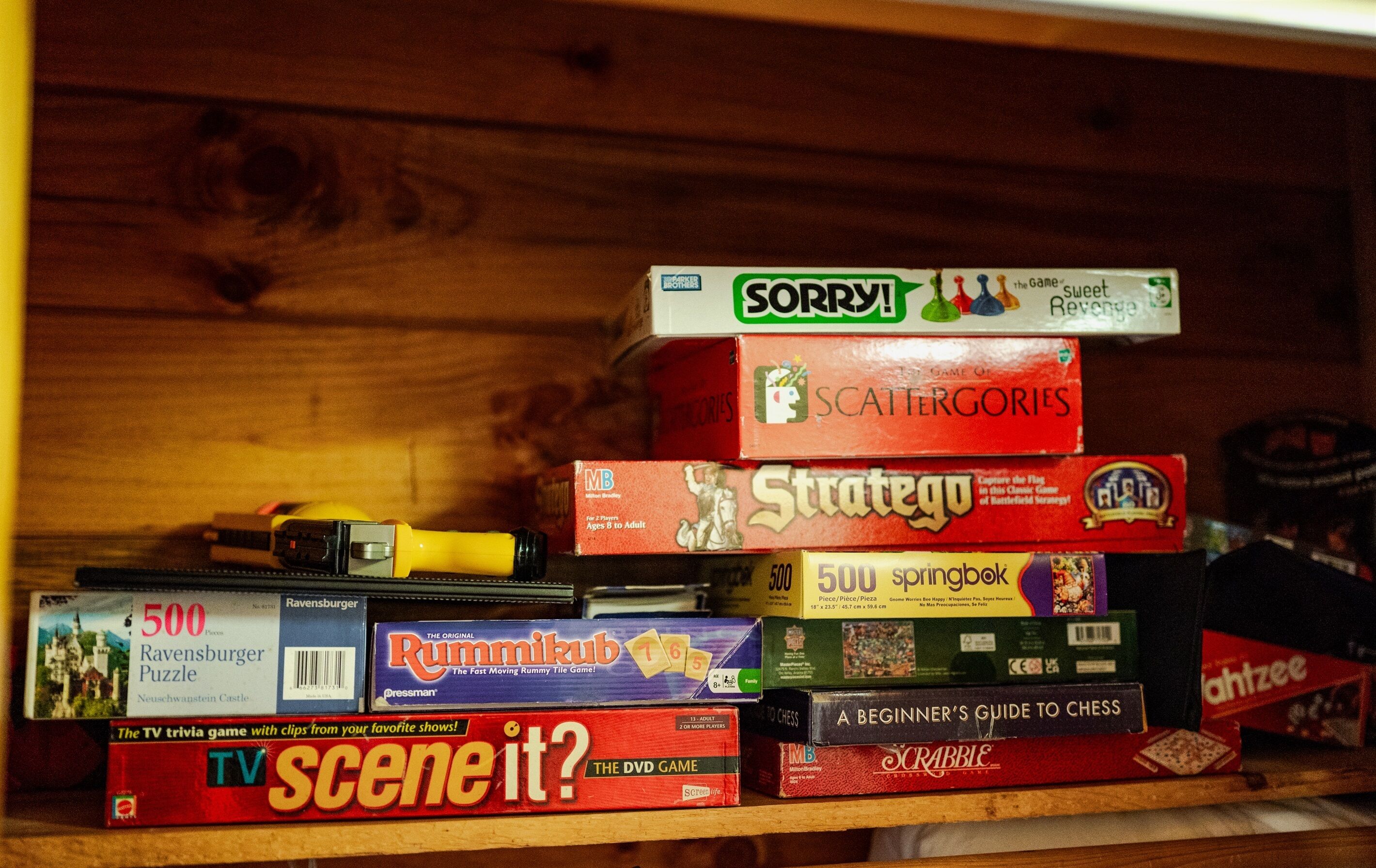 A collection of board games stacked on a shelf.