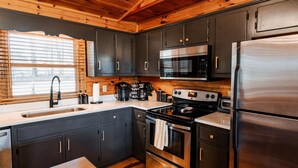 A modern kitchen with dark cabinets, stainless steel appliances, and a wooden ceiling. - 🌿 Summer Retreat  *  HotTub  *  Mountain Views  *  2 Masters  *  Pets OK (Ellijay)