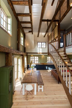 Un'ampia stanza con pavimento in legno, un grande tavolo da pranzo e una scala con ringhiere in legno.