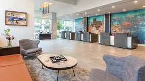 A modern lobby with a reception desk, seating area, and a large wall mural. - 1Bed/1Bath - Gorgeous Downtown Austin Resort!! (Austin)