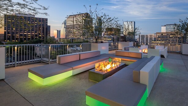 A rooftop terrace with modern seating and a central fire feature, surrounded by a city skyline at dusk. - 1Bed/1Bath - Gorgeous Downtown Austin Resort!! (Austin)