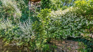 A garden with a stone wall and a wooden pergola. - Templari by Interhome (Santa Luce)