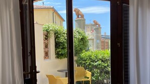 A view through a glass door to an outdoor patio area with a yellow chair, a small table, and a stone floor. - Tripyou by Interhome (Guardistallo)