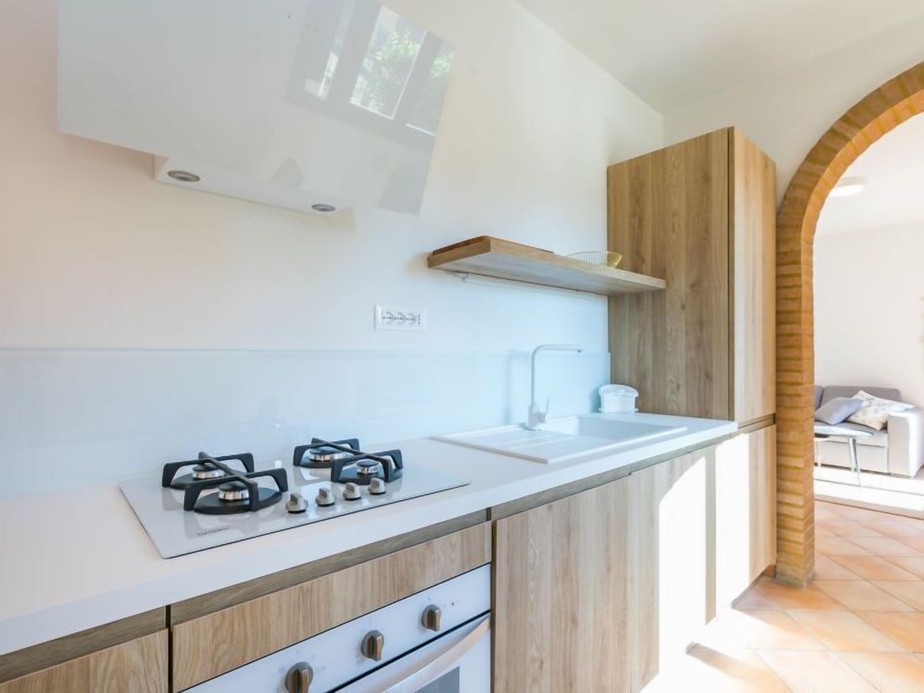 A modern kitchen with a white countertop, wooden cabinets, a built-in oven, and a gas stove.