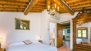 Una camera da letto con un letto di legno, un lampadario, un quadro e un soffitto rustico.