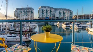 A marina with boats, a yellow table with a plant, and buildings in the background. - On the Water 4 With Free Parking By My Getaways (Brighton)