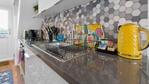 A modern kitchen with a stainless steel sink, a dish rack, and a yellow kettle. - On the Water 4 With Free Parking By My Getaways (Brighton)