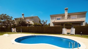 A swimming pool with a curved edge, surrounded by a paved deck and a well-maintained lawn. - Villa Mallorca by Interhome (Miami Platja)