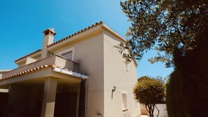 A building with a covered patio area, a small tree, and a clear blue sky. - Villa Mallorca by Interhome (Miami Platja)
