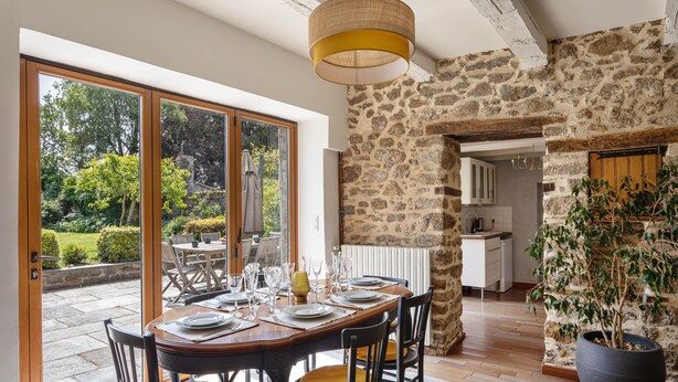 A dining area with a stone wall, a large window, and a view of the garden.